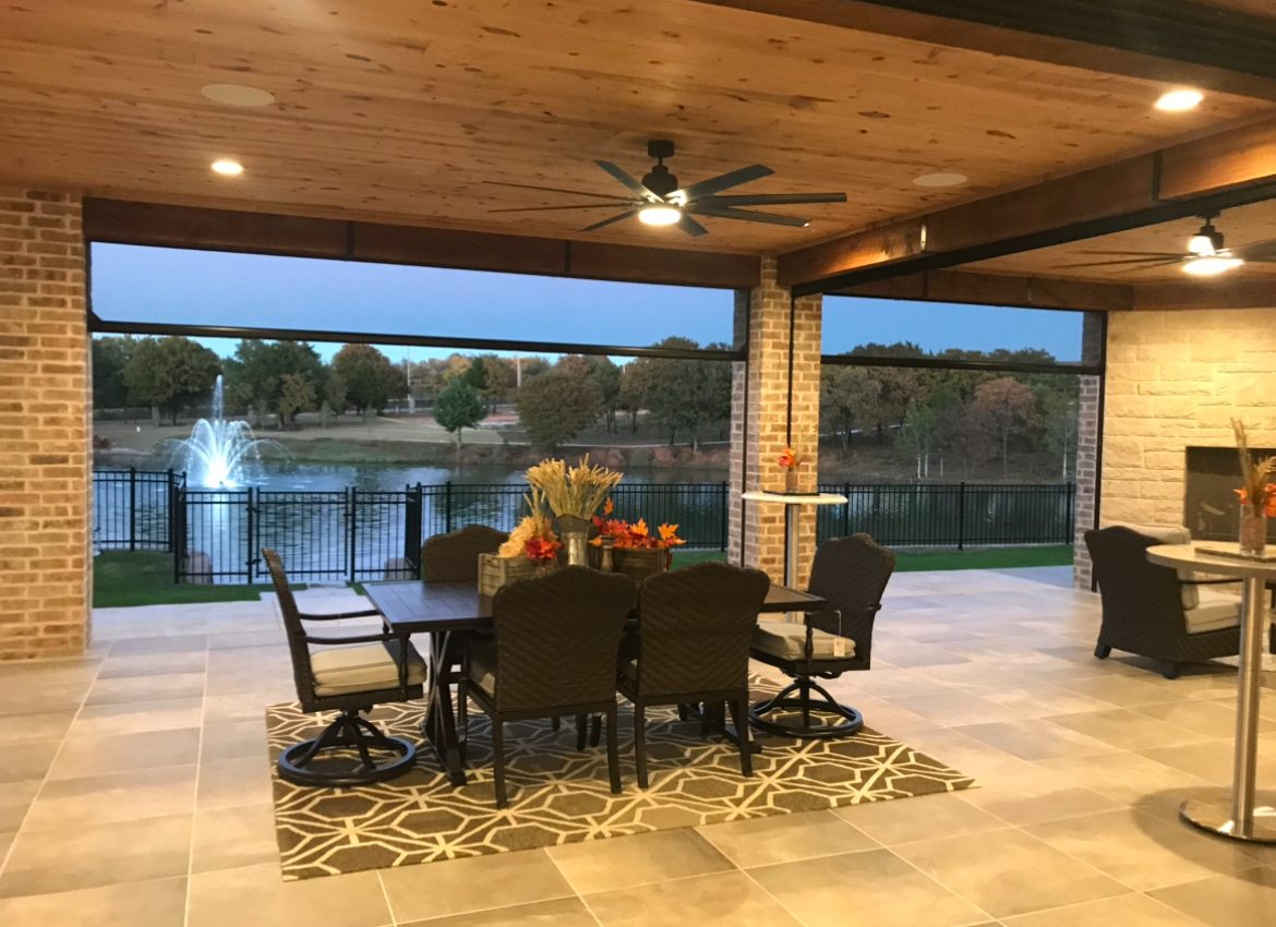 Covered patio dining area at dusk overlooking a lake fountain, enclosed with Stax motorized screens